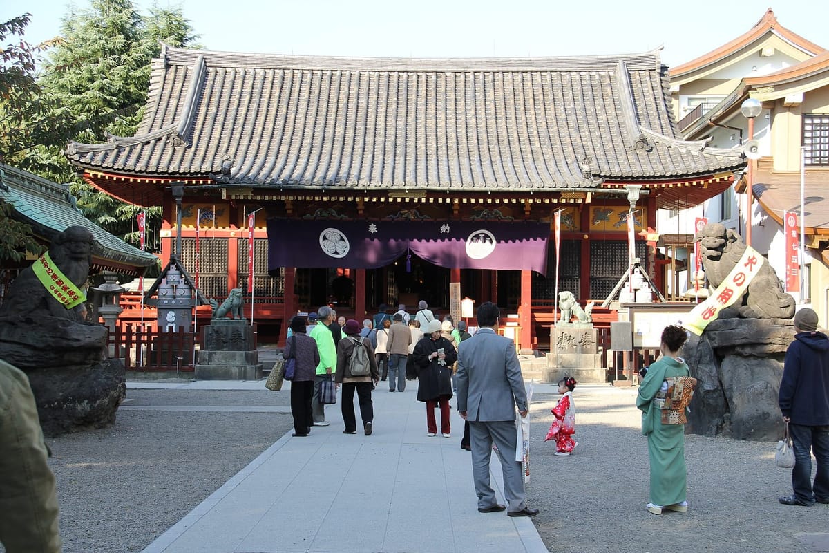 The lacquered hall of Asakusa Shrine behind its stone torii