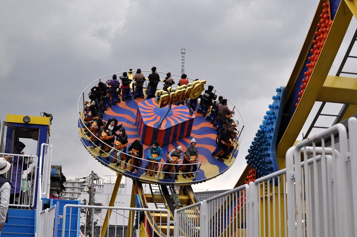 Riders on the Disk-O, one of Hanayashiki's thrill rides, swinging above the rooftops of Asakusa