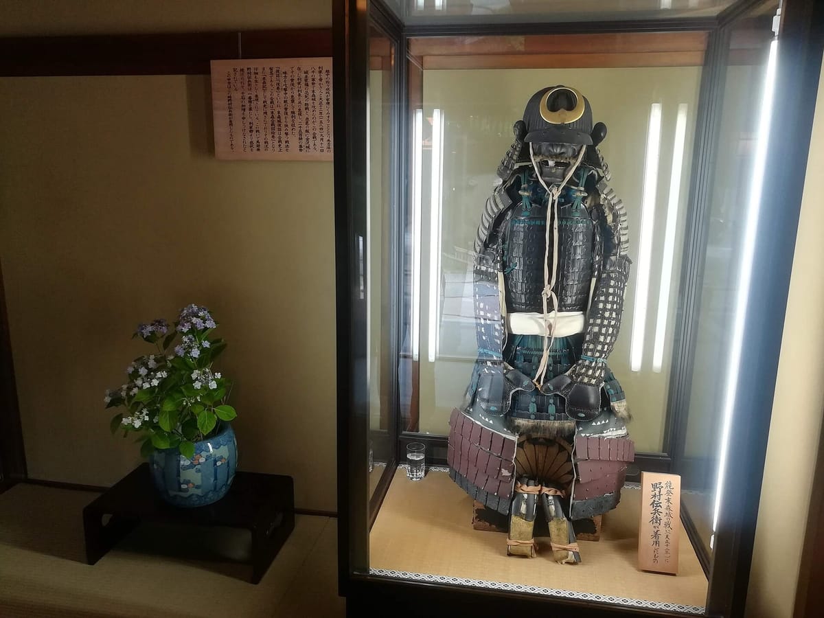 A full suit of samurai armor with helmet and face mask on display in a museum case